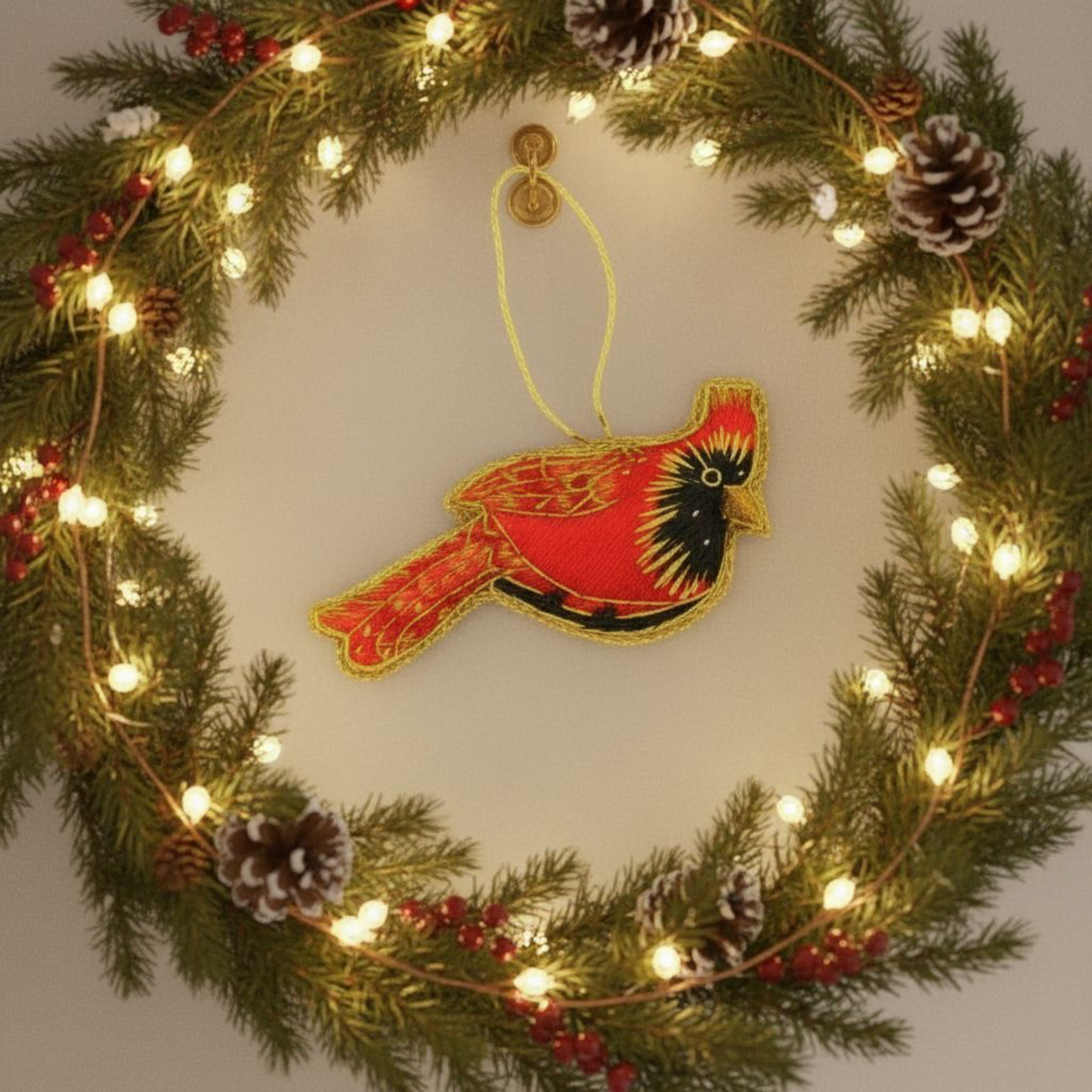 Decorative wreath with lights, pine cones, berries, and a red cardinal ornament on a plain background.