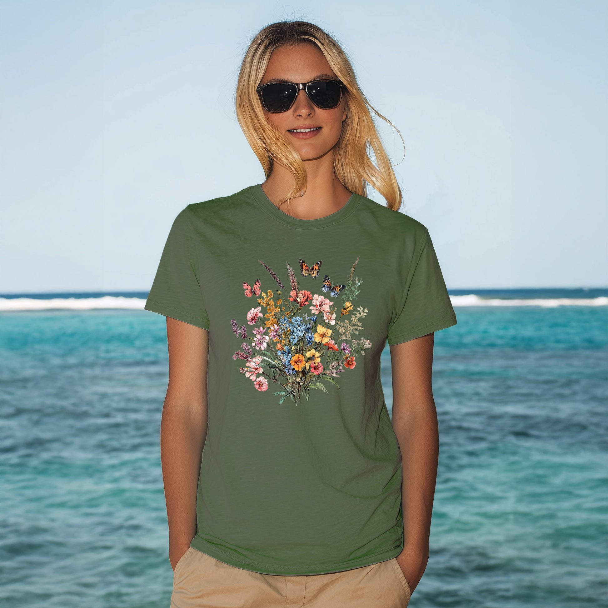 woman standing in front of the ocean wearing a vintage botanical floral butterfly t-shirt in blue spruce color. comfort colors 1717