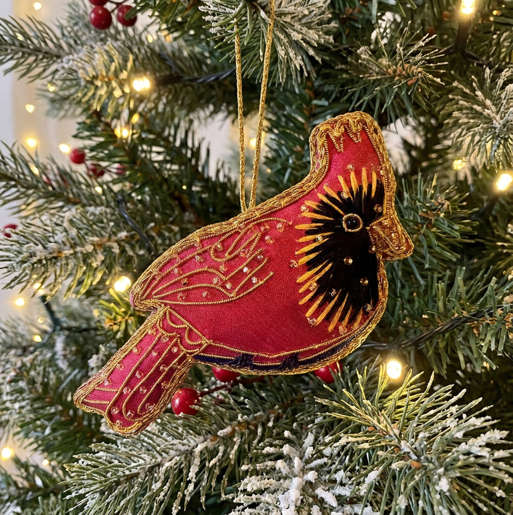 Decorative red cardinal bird ornament on a Christmas tree with lights and berries.
