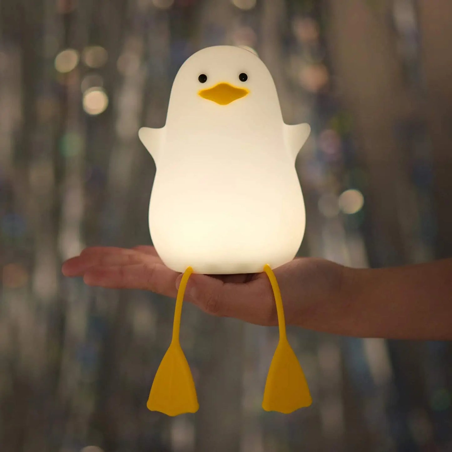 Light-up duck-shaped toy held in a hand with a blurred background