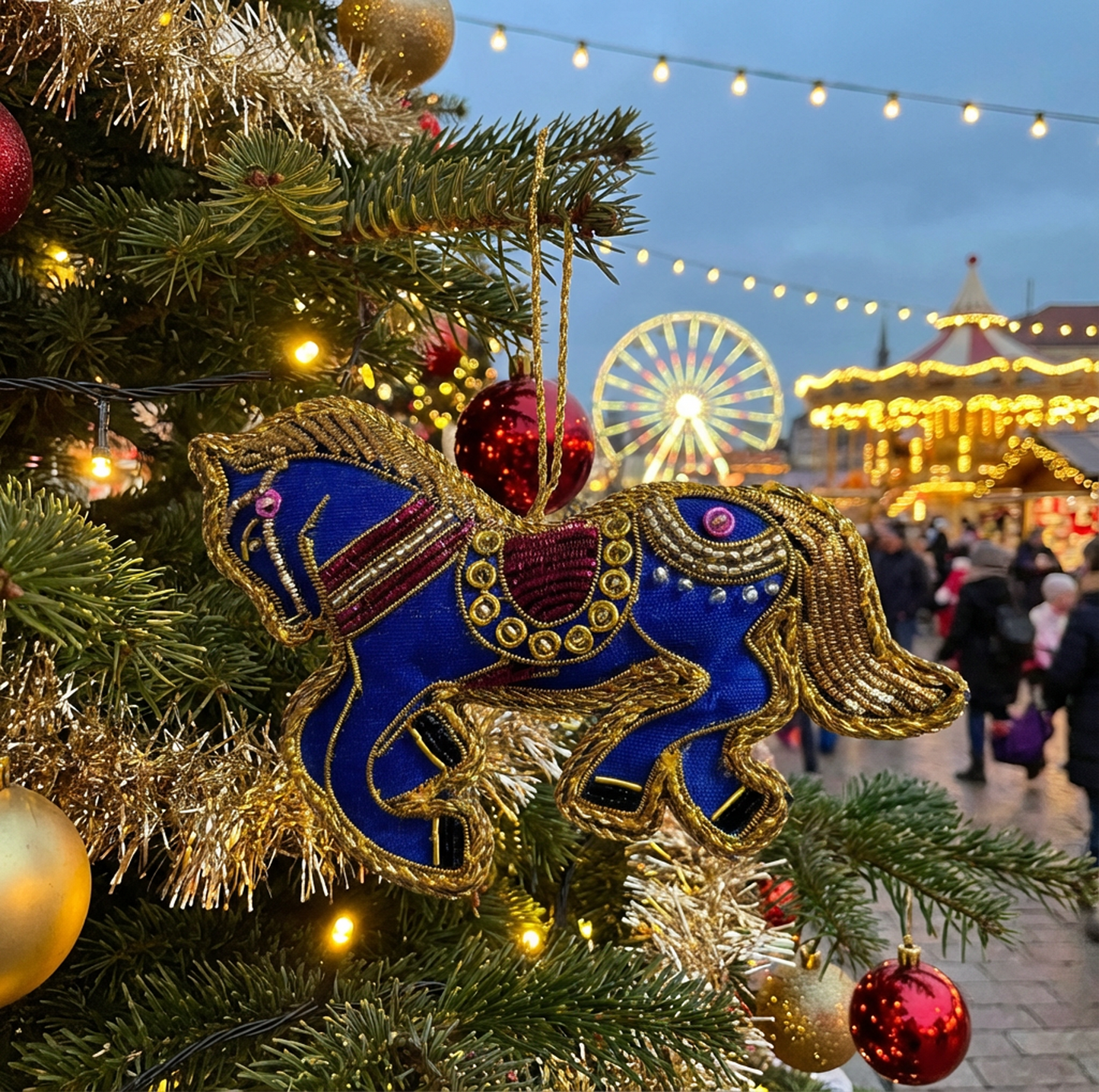 Decorative Christmas tree with a blue and gold horse ornament, festive lights, and a carousel in the background.